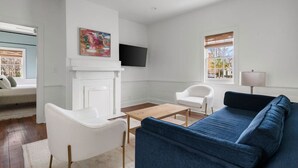 Una sala moderna con un sofá azul, sillones blancos, una mesa de centro de madera y una chimenea.