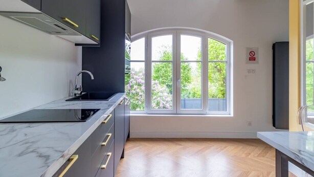 Une cuisine moderne dotée d’une grande fenêtre, d’un plancher en bois et d’armoires encastrées.