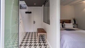 Une chambre à coucher moderne, avec un lit, un banc et une porte donnant sur une salle de bain.