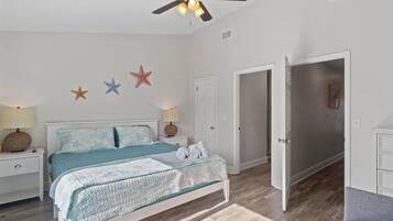 A bedroom with a bed, nightstands, a ceiling fan, and star decorations on the wall.