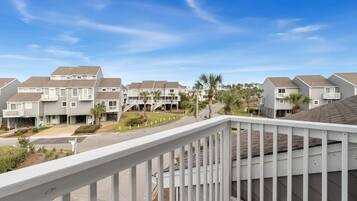 A residential complex with multiple two-story buildings, a central courtyard with palm trees, and a clear blue sky.