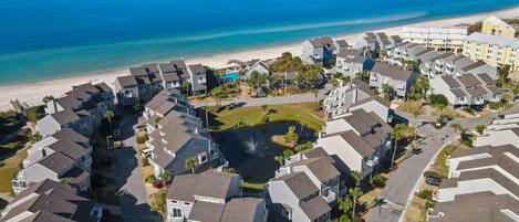 A coastal residential area with multi-story buildings, a beach, and a small water body.