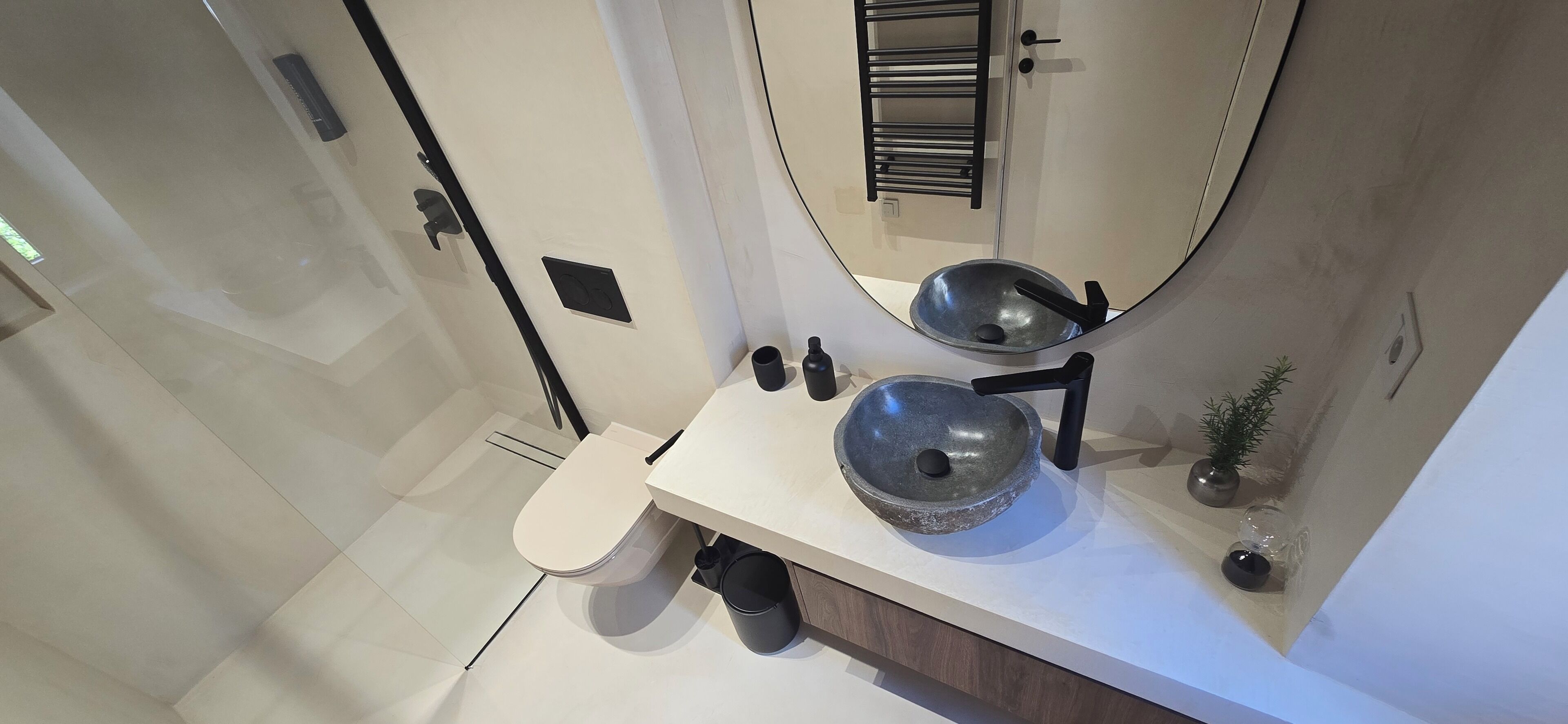 A modern bathroom with a white sink, a round basin, and a toilet.