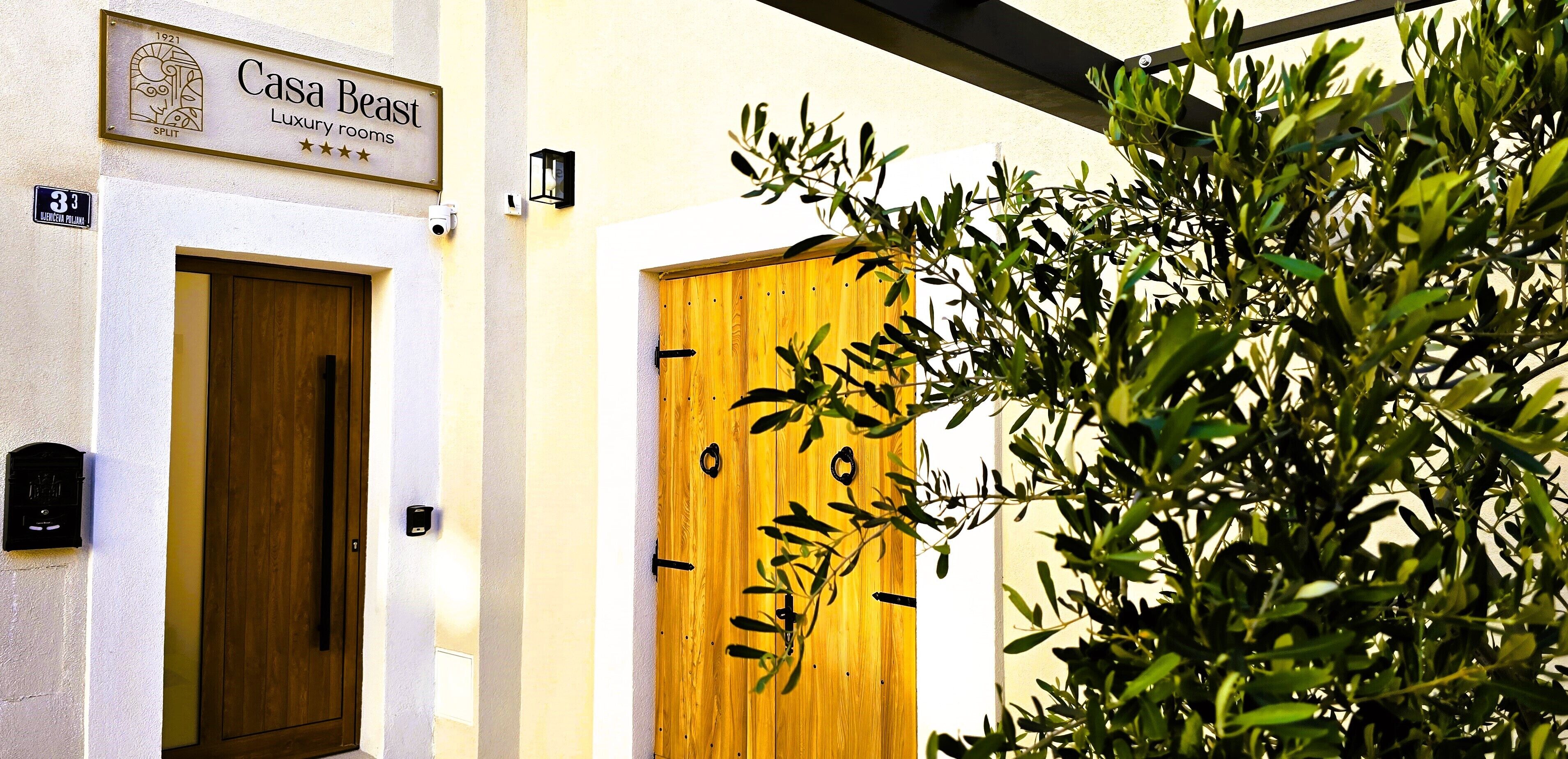 Entrada de un edificio con un cartel que dice 'Casa Beasts Luxury rooms' y una puerta de madera.