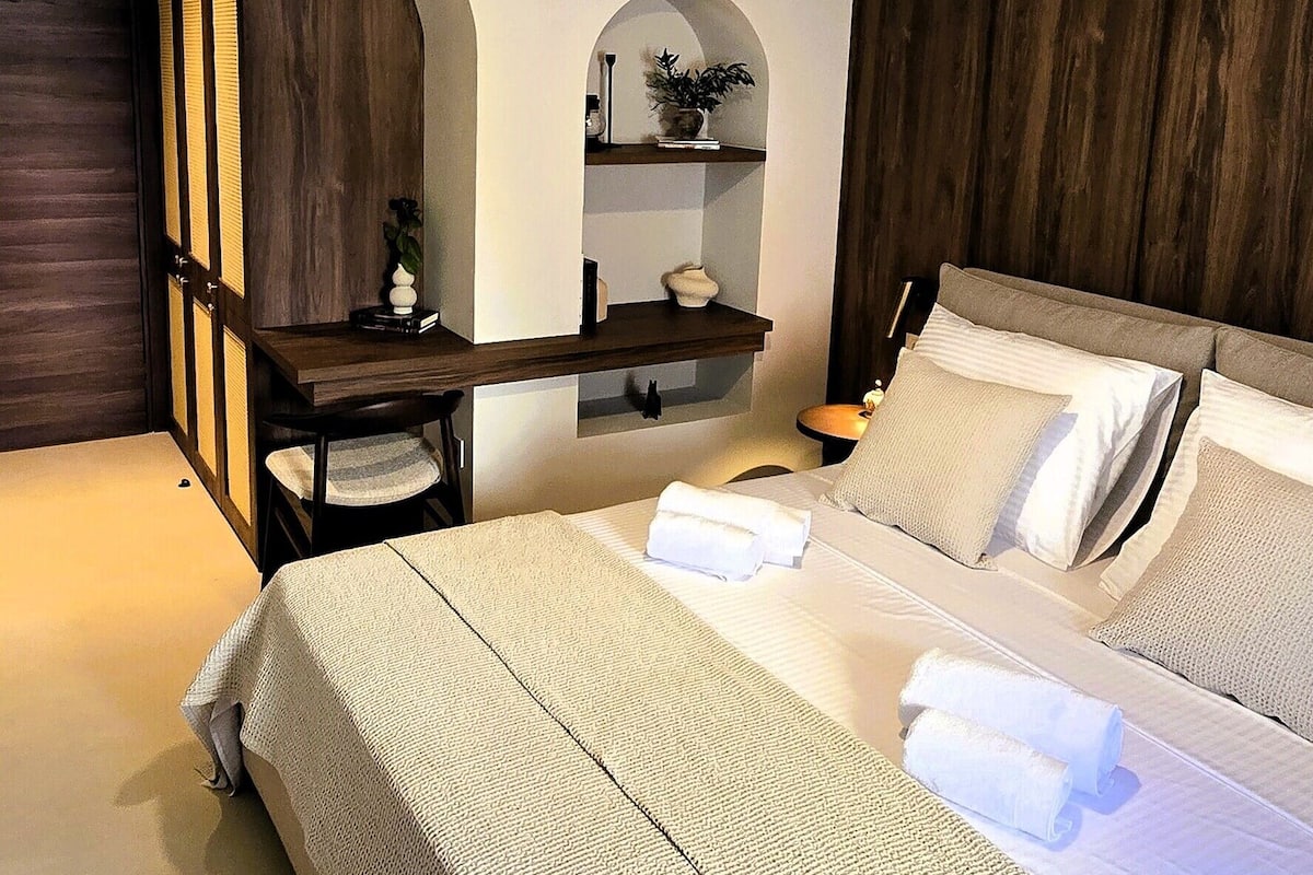 Una camera da letto con un letto, una scrivania, una sedia, una ventola a soffitto e un comodino.