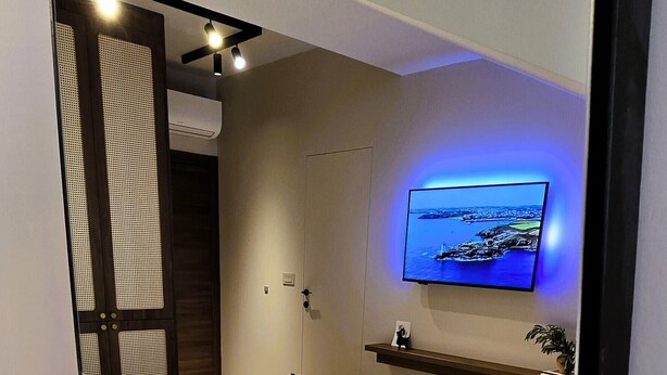 A modern hotel room with a bed, a TV mounted on the wall, and a small shelf with towels. - Casa Beast (Split)