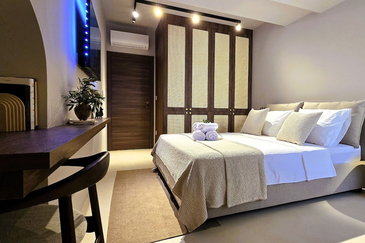 Una camera da letto moderna con un letto, un comodino, una sedia e un tavolino rotondo.