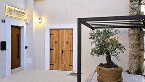 A wooden door with a metal handle, a sign above it, and a potted tree in the foreground. - Casa Beast (Split)