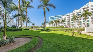 A resort with a pool, palm trees, and a modern building with multiple balconies. - Condo Aria Ocean 614 by Kivoya (Nuevo Nayarit)