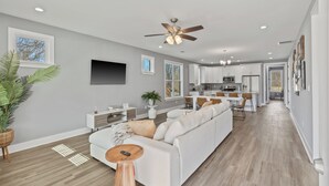 A modern living room with a white sofa, a coffee table, and a ceiling fan. - Cozy 3BR Home - Fire Pit & Gated Parking in Midtown - Near Rhodes College & Zoo (Memphis)