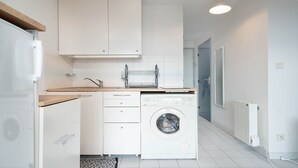 Eine kleine Küche mit Waschmaschine, Spüle und Wäscheständer.