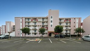 Ein mehrstöckiges Hotel mit Innenhof, Parkplatz und mehreren Bäumen.