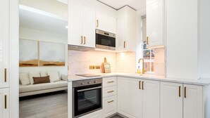 Une cuisine moderne avec des meubles blancs, un four encastré et un four à micro-ondes.
