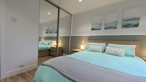 Ein modernes Schlafzimmer mit einem großen Bett, Nachttischen und einer Schiebetür zu einem weiteren Raum.