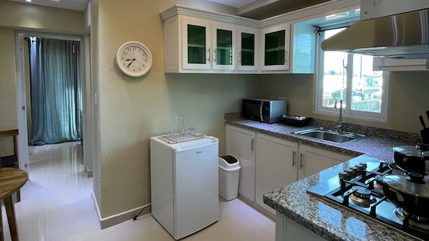 Une cuisine moderne avec des meubles blancs, un four à micro-ondes encastré, une cuisinière à gaz et un réfrigérateur.