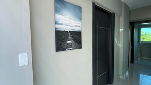 Un couloir avec une porte, un interrupteur et un tableau encadré au mur.