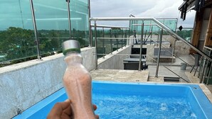 Une main tenant un salière au-dessus d’une piscine bleue.