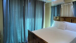 Une chambre avec un lit en bois, un ventilateur de plafond et un appareil de climatisation.