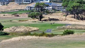 Ein Golfplatz mit Klubhaus und Wohnhäusern im Hintergrund.
