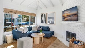Een moderne woonkamer met een hoekbank, een ronde salontafel en een open haard.