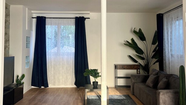 Un salon avec un plancher en bois, un canapé, une table basse et un téléviseur.