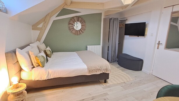 A bedroom with a bed, bedside lamps, a mirror, a television, and a door with a window. - Studio Notre Dame 3 in the heart of town, 30 minutes from the Puy du Fou park (Cholet)