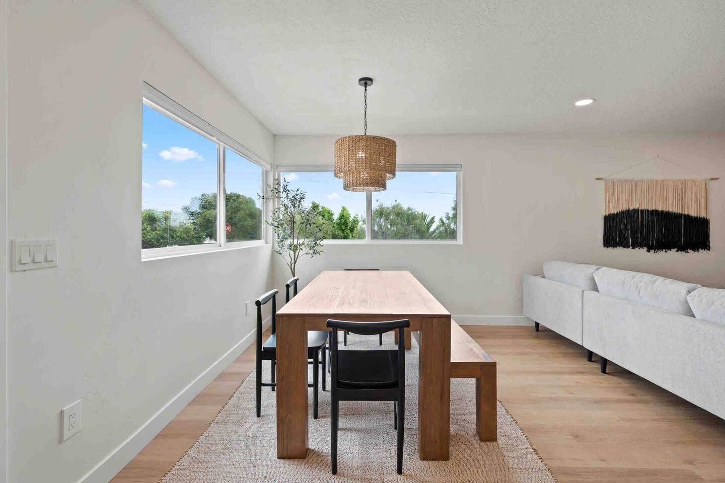 A modern dining room with a wooden table, chairs, and a hanging light fixture.
