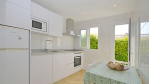 A modern kitchen with white cabinets, a microwave, a stove, and a window overlooking greenery.