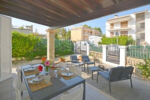 Eine Außenpatio mit einem für zwei Personen gedeckten Tisch, umgeben von Stühlen, und Blick auf ein Wohngebiet mit Gebäuden und Grünflächen.