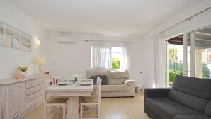 A living room with a dining table, a sofa, and a window with curtains.