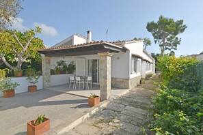 Ein Haus mit Terrasse, Sitzgelegenheiten im Freien und Blumentöpfen.