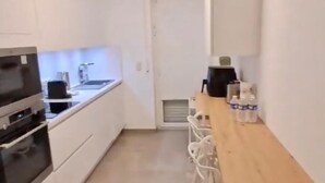 Una cocina estrecha con armarios blancos, encimera de madera y horno empotrado.