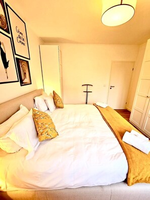 Une chambre d’hôtel avec un grand lit, une table de chevet, une lampe et une armoire.
