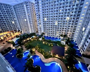 A high-rise hotel with multiple floors, a central courtyard with a swimming pool, and surrounding greenery. - Live Just Steps Away From Mall of Asia (Pasay)