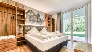 A modern bedroom with a large bed, wooden wardrobe, and a mural of a house.