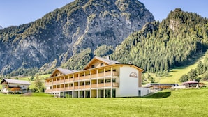 A hotel with a multi-story structure, a balcony, and a mountain backdrop. - Brandnerhus Nr 25 - Balkon 4-zimmer Ferienwohnung (Brand)