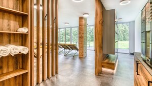 A modern hotel lobby with wooden shelving, a massage chair, and a large window offering a view of the outdoors. - Brandnerhus Nr 25 - Balkon 4-zimmer Ferienwohnung (Brand)