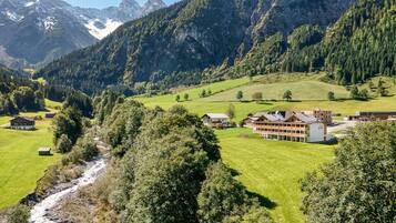 A mountain landscape with a river, houses, and a large building with multiple rooms.