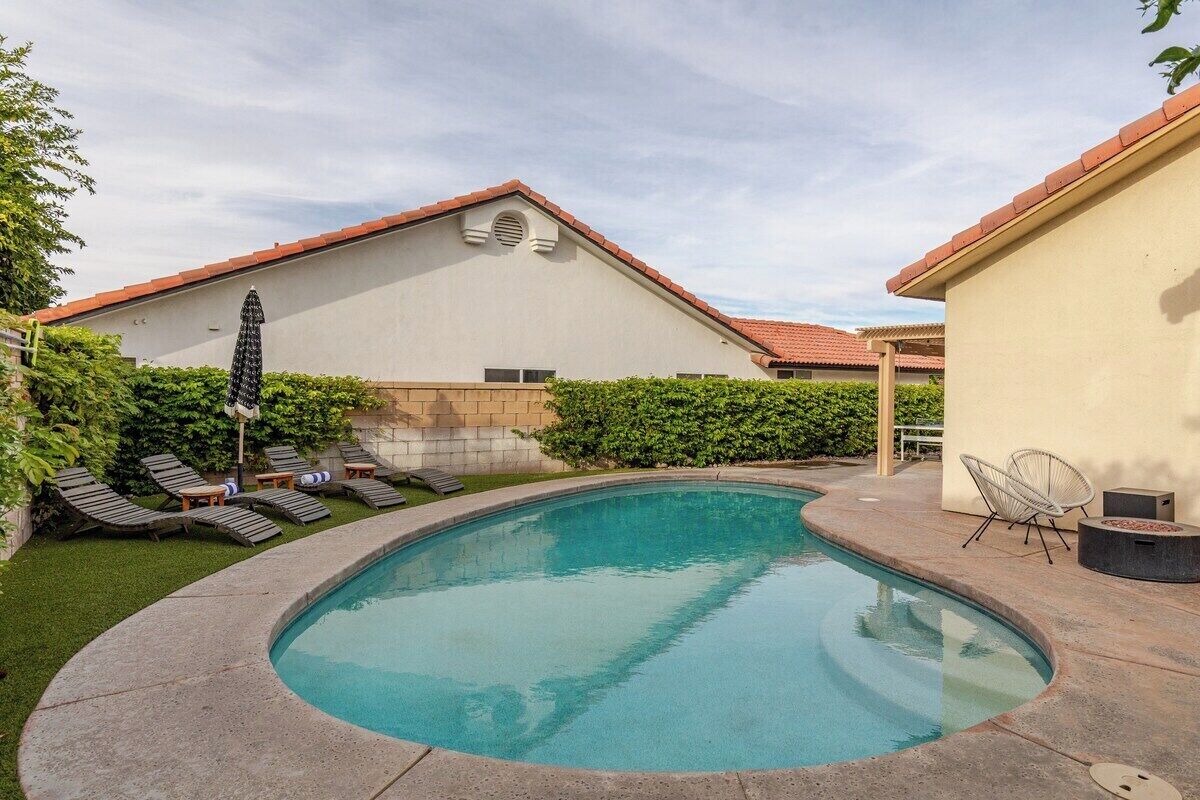 A swimming pool with lounge chairs and a small patio area.