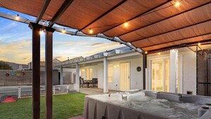 An outdoor patio area with a hot tub, covered seating, and a view of the surrounding landscape. - 3BD Pool+Jacuzzi Oasis! (North Las Vegas)