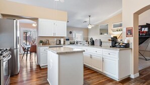 A modern kitchen with white cabinets, a central island, and a ceiling fan. - 3BD Pool+Jacuzzi Oasis! (North Las Vegas)