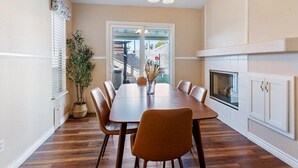 A dining area with a wooden table, chairs, a chandelier, a potted plant, and a fireplace. - 3BD Pool+Jacuzzi Oasis! (North Las Vegas)