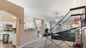 A spacious living area with a kitchen, a staircase with a basketball hoop, and a small play area. - 3BD Pool+Jacuzzi Oasis! (North Las Vegas)