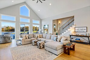 A spacious living room with a large sectional sofa, a patterned rug, and a view of a lake.
