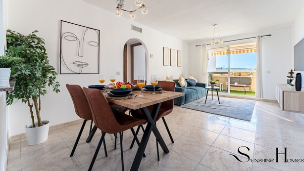 A modern living room with a dining area, a large plant, and a view of the outdoors.