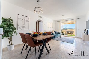Un salon moderne avec un coin repas, une grande plante et une vue sur l’extérieur.