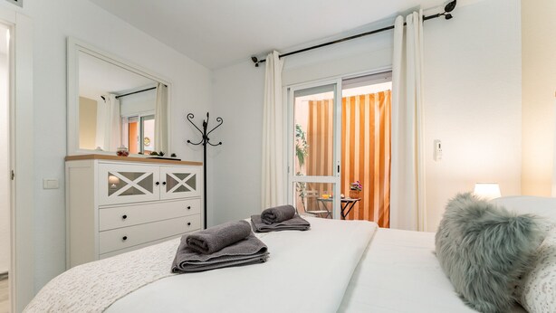 A hotel bedroom with a bed, a dresser, a coat rack, and a view of the outside. - 50 Meters from the Beach, 1 Bedroom with Parking REF013 (Torremolinos)