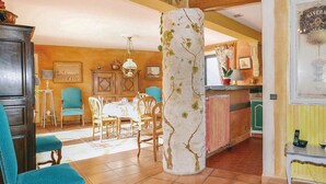 Un comedor con una mesa lista para cuatro personas, rodeada de sillas, en una habitación con armarios de madera y un gran pilar con diseño de árbol.