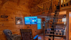 A cozy cabin interior with a wooden interior, a mounted TV, a fishing sign, and a staircase. - Lazy Lake Days • Fast Wifi • Roku TV • Free Firewood (Alpine)