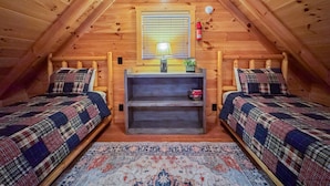 A cozy attic bedroom with two beds, a small shelf, and a window with blinds. - Lazy Lake Days • Fast Wifi • Roku TV • Free Firewood (Alpine)